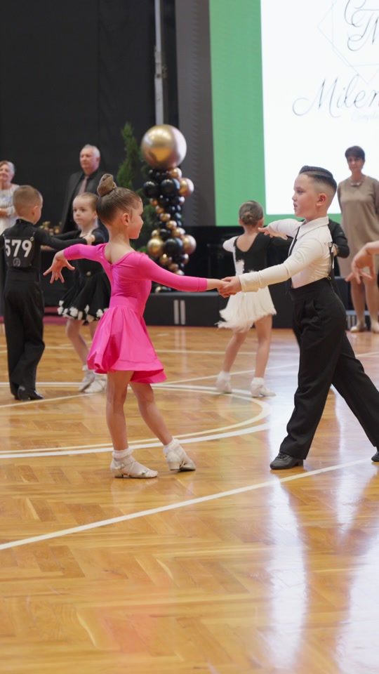 Doi copii de aproximativ 6 ani dansând cha-cha în sala Spotlight
